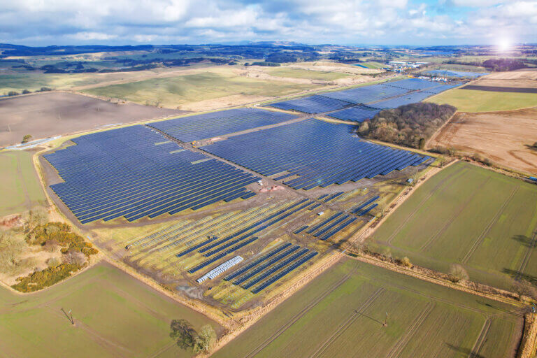 A BELECTRIC solar farm shown from above. In the distance, you can see hills and the sun setting.