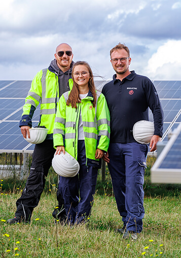 Three BELECTRIC employees who help offer holistic BESS solutions stand in front of a solar farm.